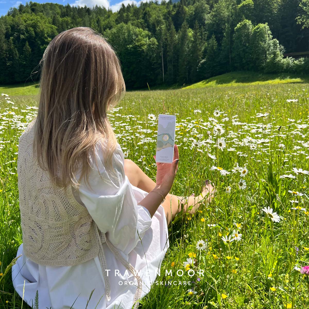 DR SPILLER TRAWENMOOR Hydro Cream – 50 ml, Frau auf Blumenwiese sitzen hält Umverpackung