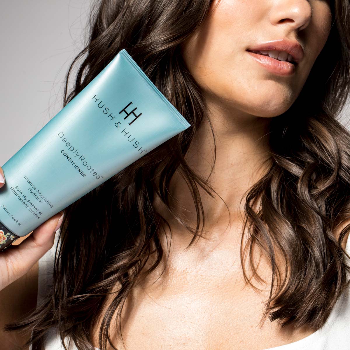HUSH & HUSH DeeplyRooted Conditioner – 200ml, Frau hält Tube