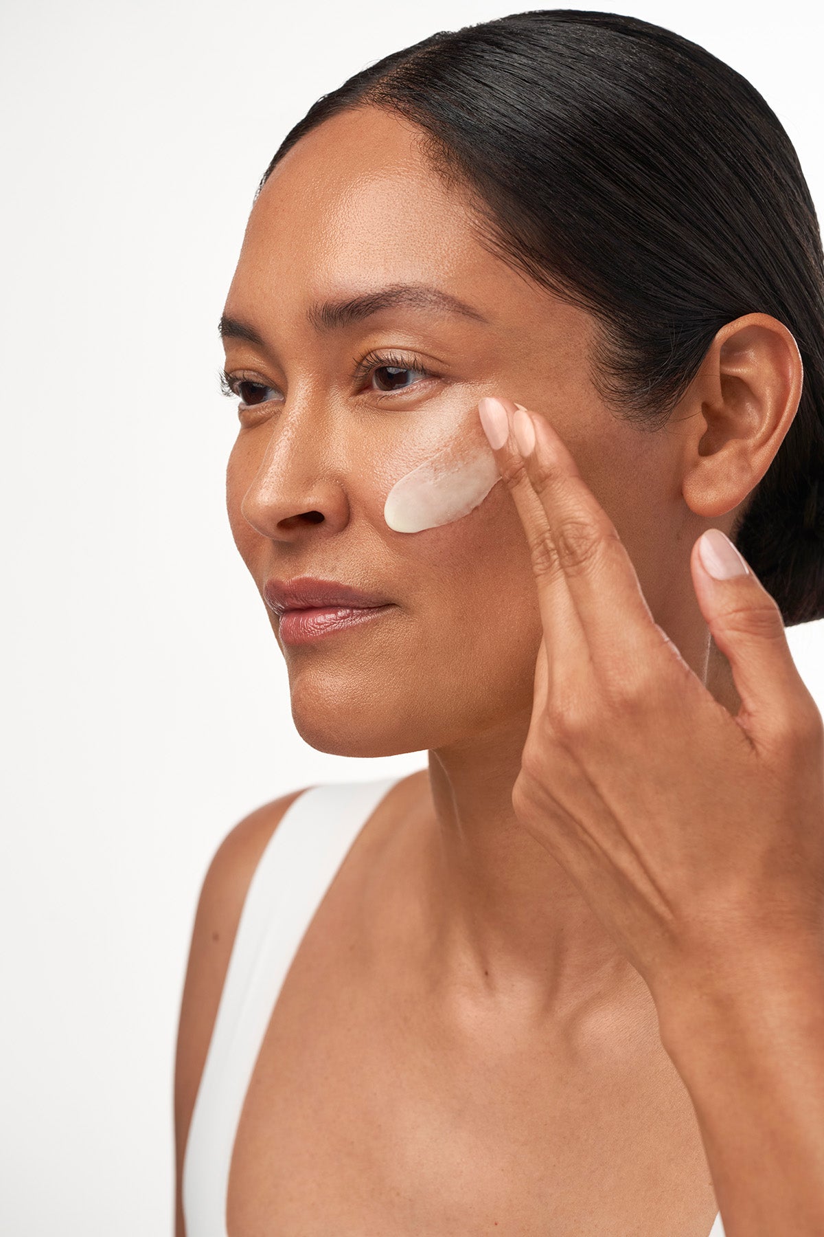 IMAGE SKINCARE MD biotech longevity crème – Reisegröße, 16g, Frau trägt Creme auf Gesicht auf