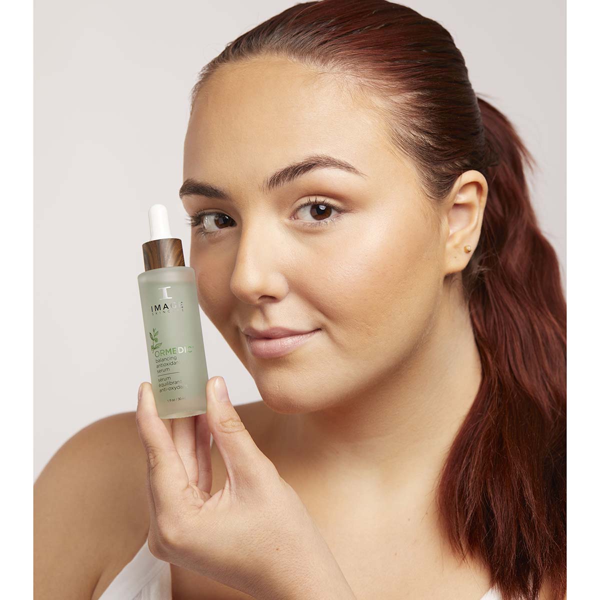 IMAGE SKINCARE Ormedic Balancing Antioxidant Serum – Feuchtigkeitsspendendes Serum, 30ml, Frau hält Serum neben Gesicht