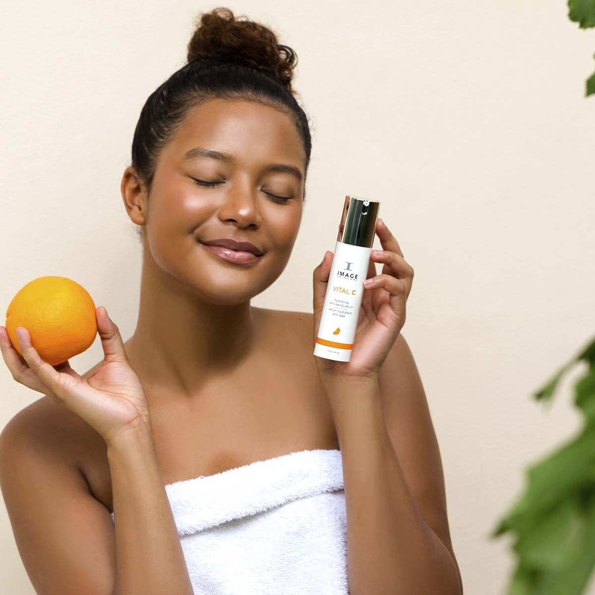 IMAGE SKINCARE Vital C Hydrating Anti-Aging Serum – 50ml, Frau hält Serum und Orange