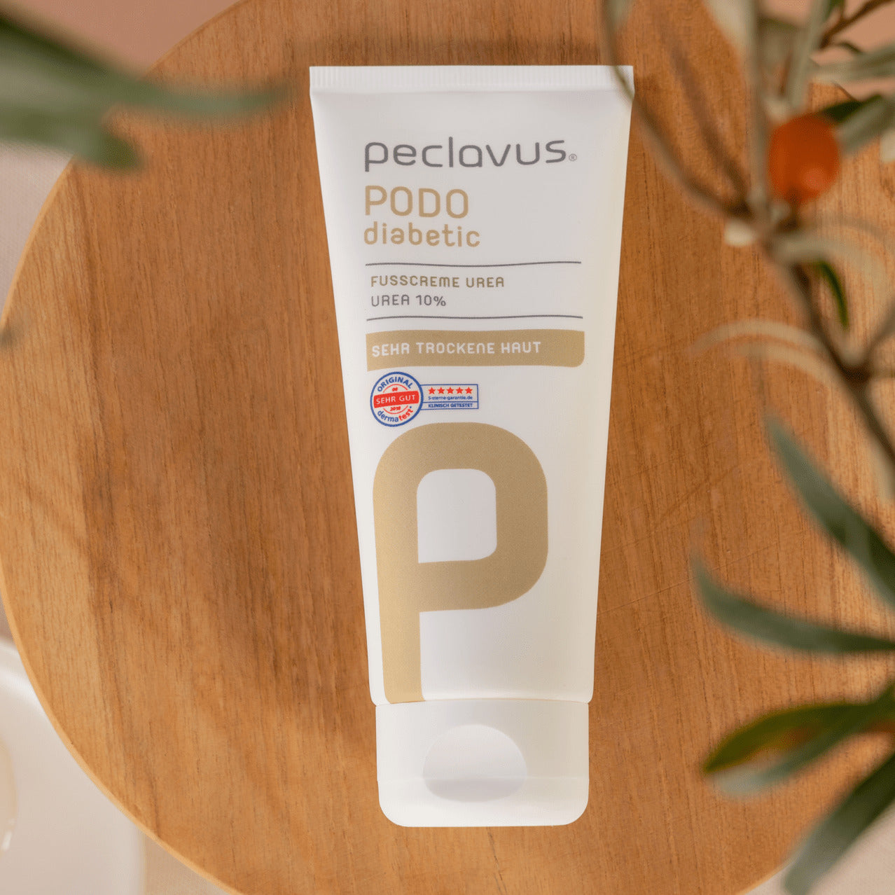 PECLAVUS Fußcreme Urea – 100ml, Tube liegend auf Holzteller