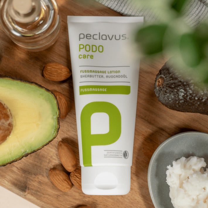 peclavus Fußmassage Lotion – 100ml, Tube auf Holz liegend mit Nüssen und Avocado