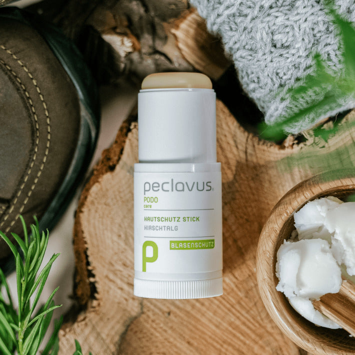 PECLAVUS Hautschutz Stick – 23g, Stick offen auf Holz liegend neben Wanderschuh und Schal
