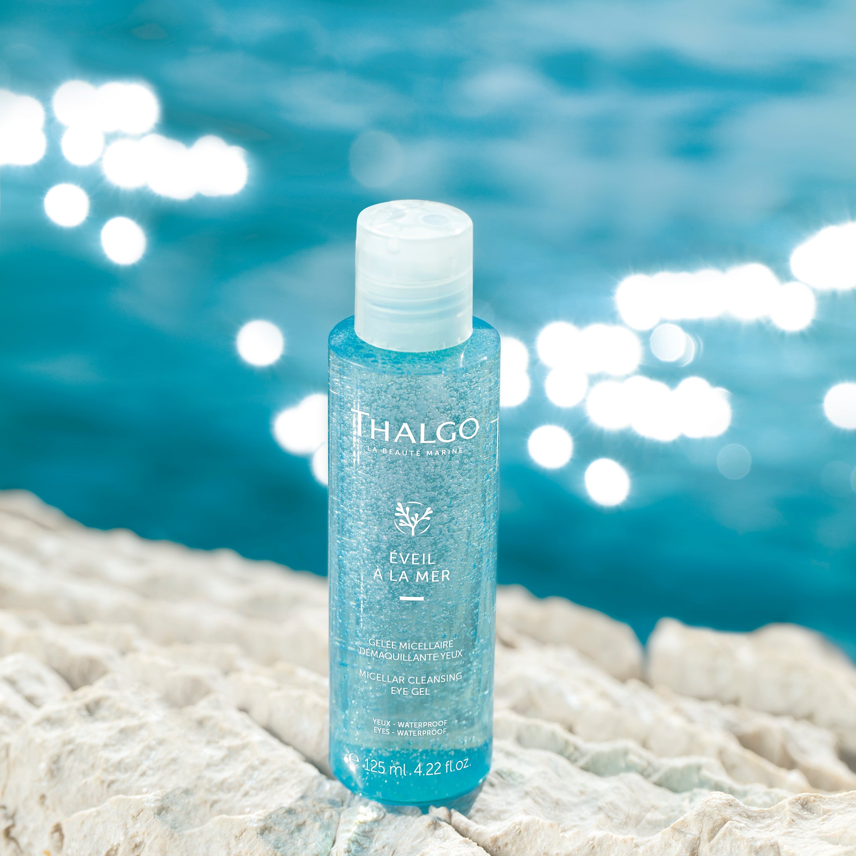 THALGO Éveil à la Mer - Mizellen Augen-Reinigungsgel – 125ml, Spender auf Sand neben Meerwasser