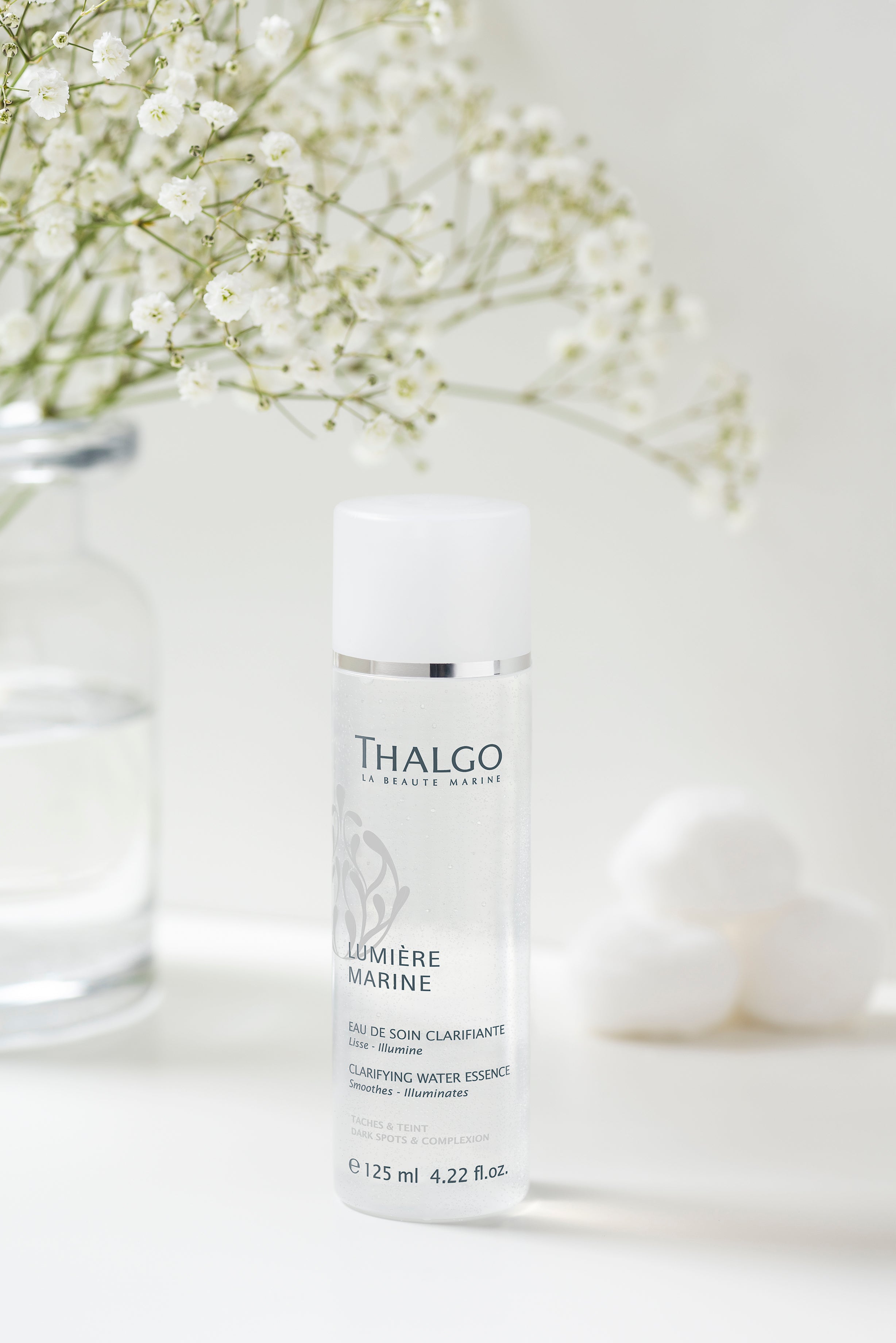 THALGO Lumière Marine - Brightening-Essenz – 125ml, Spender auf Tisch mit Schmuck und Blumenstrauß