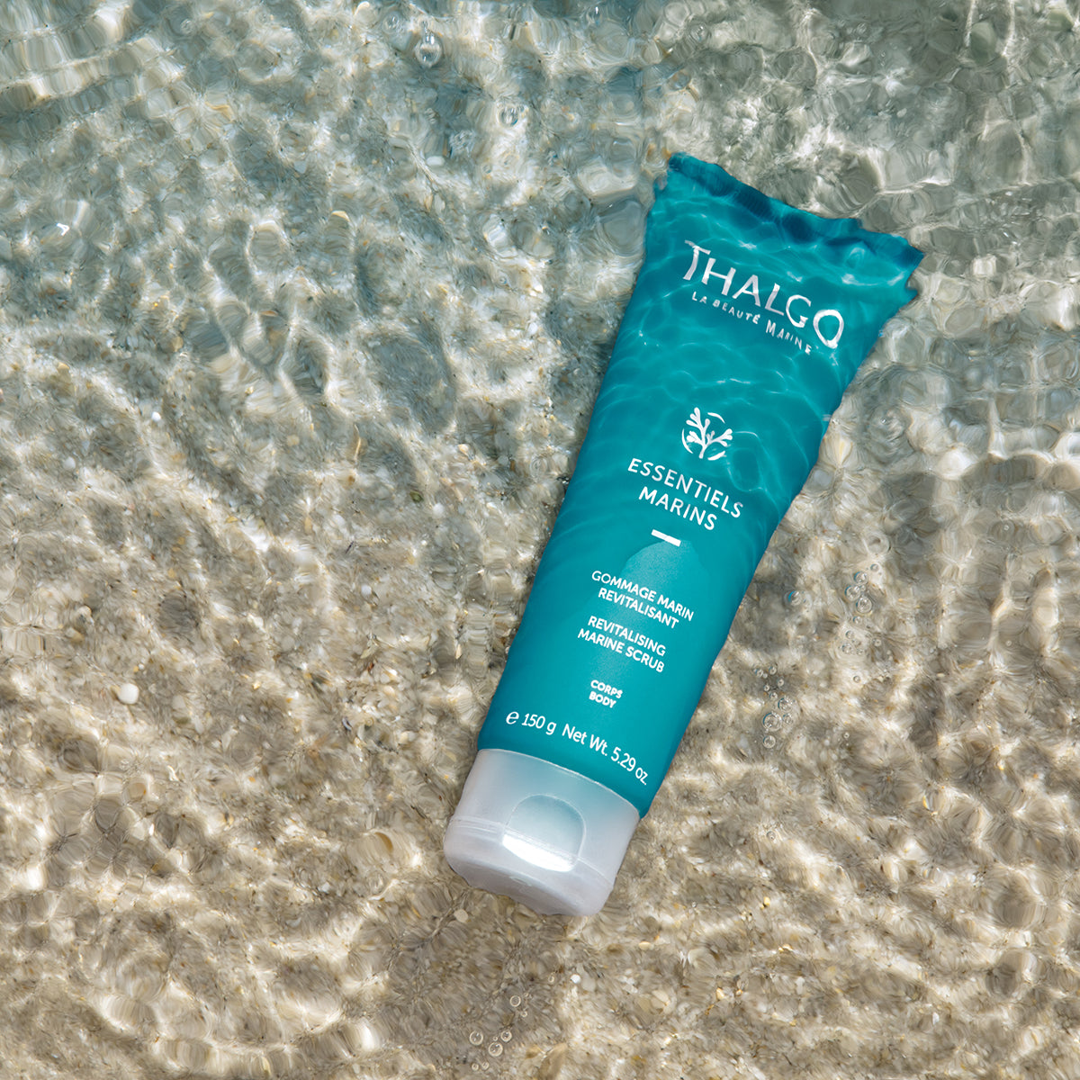 THALGO Marine Essentials - Revitalisierendes Körperpeeling – 150ml, Tube auf Sand unter Wasser