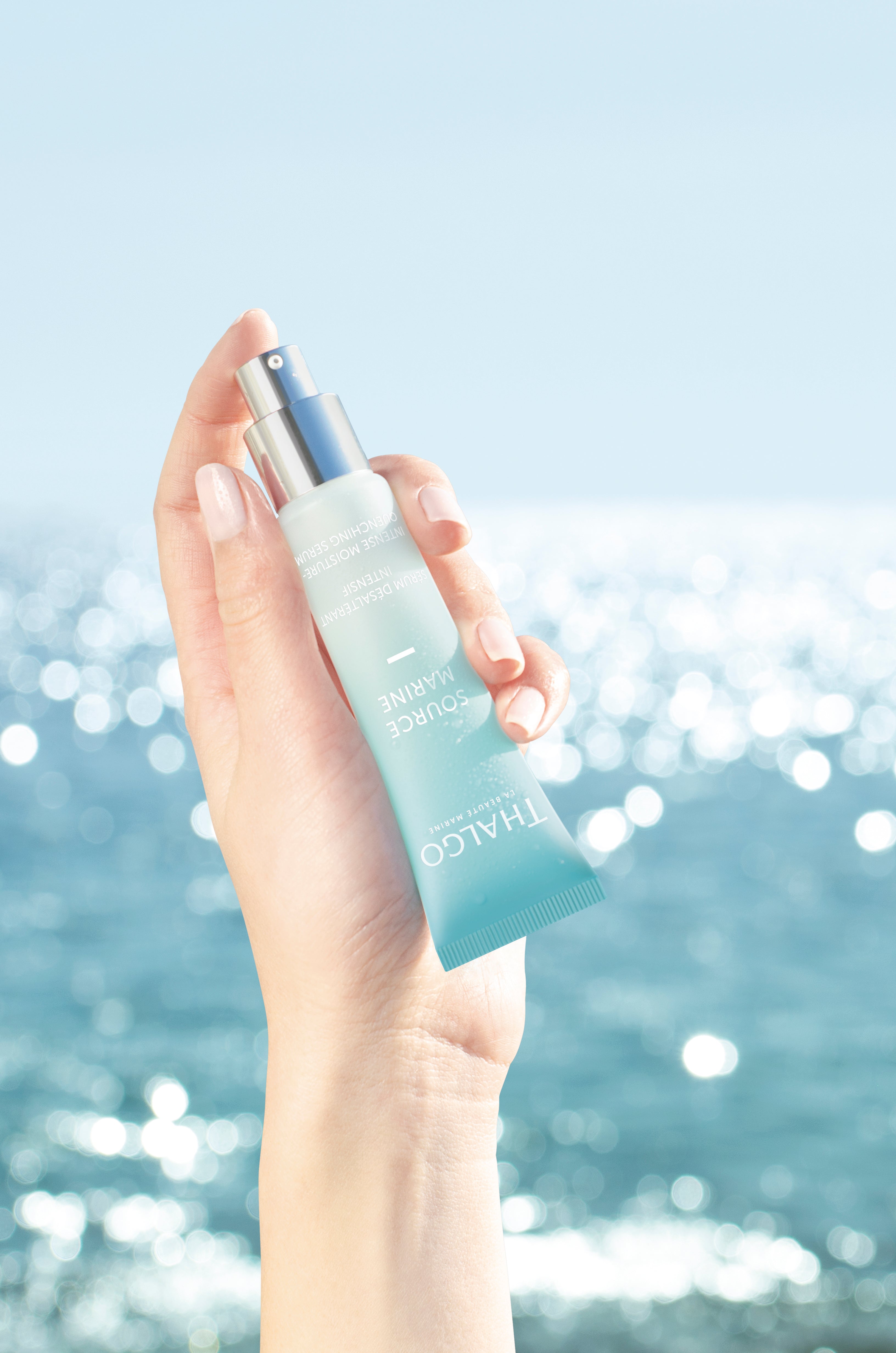 THALGO Source Marine - Intensiv-Feuchtigkeits-Serum – für trockene Haut, 30ml, Hand hält Tube vor Meereshintergrund