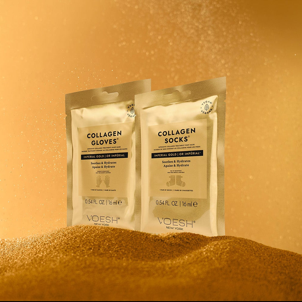 VOESH Collagen Gloves and Socks Imperial Gold – luxuriöse Handmaske und Fußmaske mit Kollagen, 2 Paar, Verpackungen auf Sand vor goldenem Hintergrund