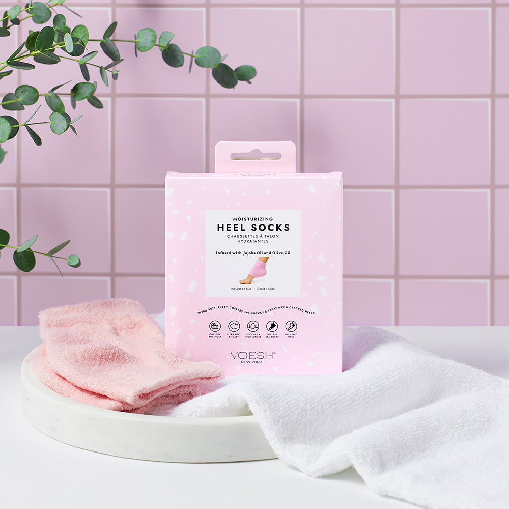 VOESH Moisturizing Heel Socks – rosa, 1Paar, Umkarton Socken und Handtuch in Keramikschale vor rosa Fliesenwand