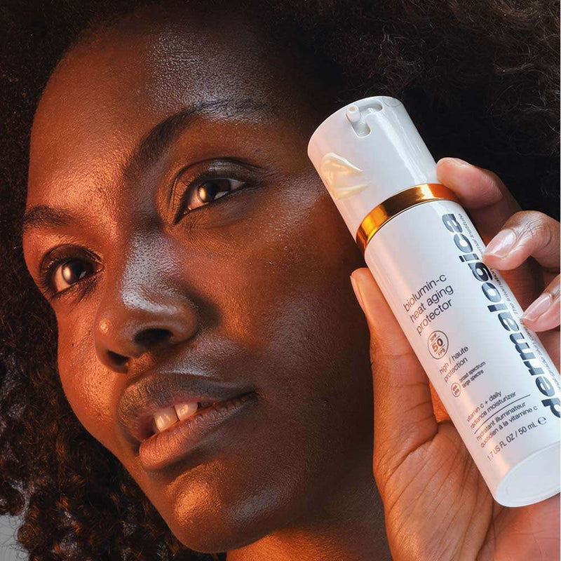 DERMALOGICA Biolumin-C Heat Aging Protector SPF50 – Mit feuchtigkeitsspendenden Inhaltsstoffen und ultrastabilem Vitamin C bietet der neue Biolumin-C Heat Aging Protector SPF 50 optimalen Schutz vor Anzeichen der Hautalterung., 50ml, Frau zeigt Produkt