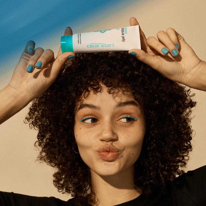 DERMALOGICA Clear Start Cooling Aqua Jelly – Ein ultraleichtes Gel für ölige Haut, das erfrischt und kühlt. Dieser Moisturizer verfeinert das Hautbild und&nbsp;spendet viel Feuchtigkeit ohne zu fetten. So pflegt es ölige&nbsp;Haut optimal., 59ml, Frau zeigt Tube