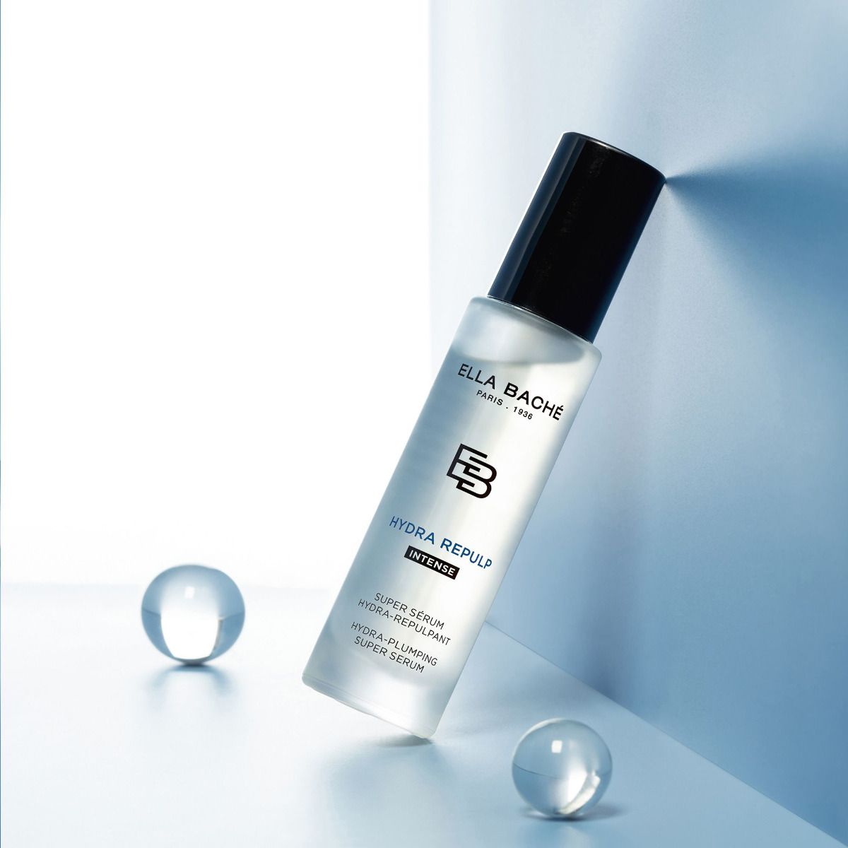 ELLA BACHE HYDRA REPULP - Hyaluron Powerserum  – Anti-Aging-Serum, 30ml, Pumpspender vor blauem Hintergrund mit Glaskugeln
