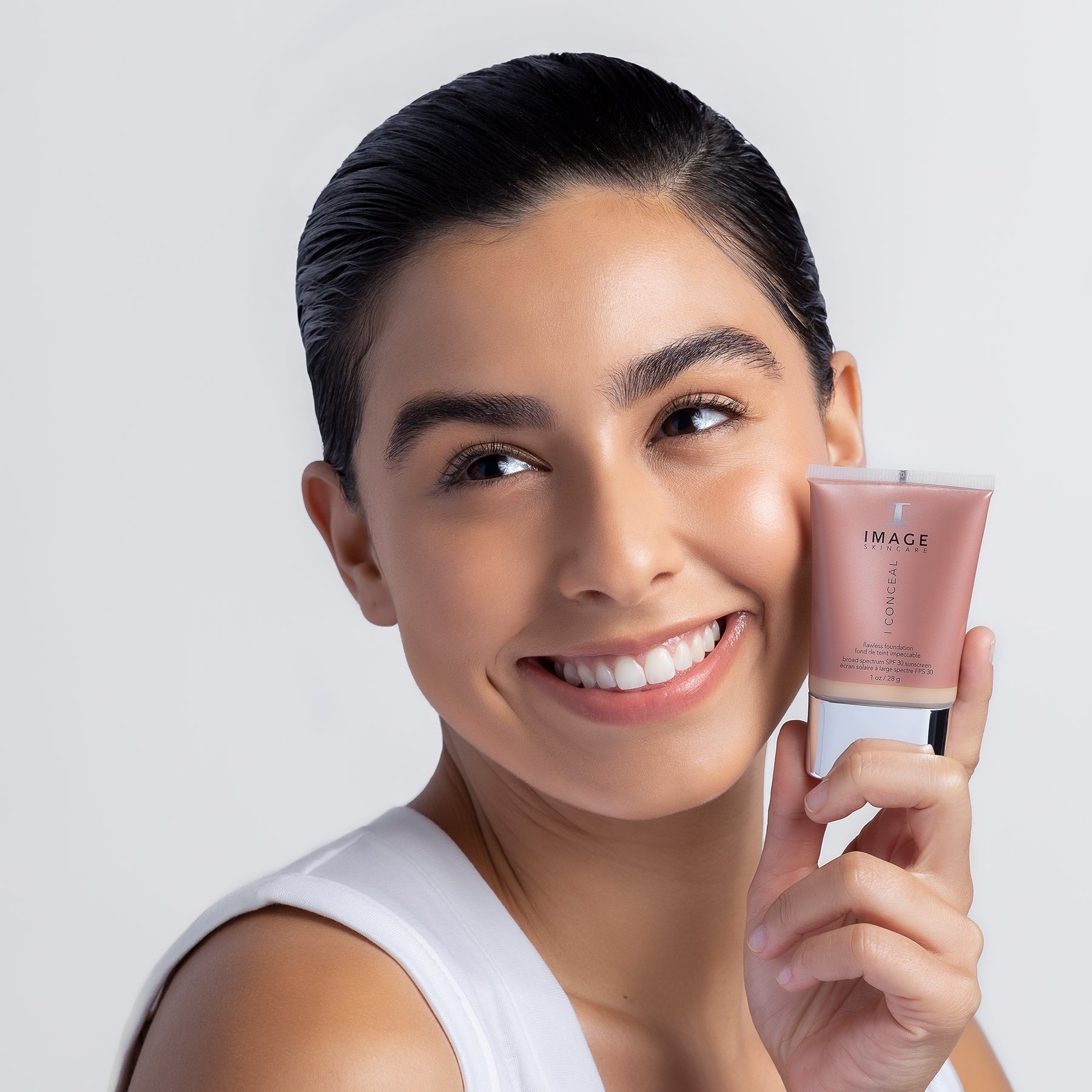 IMAGE SKINCARE I conceal flawless foundation SPF 30 – suede , 28g, Frau hält Tube neben Gesicht