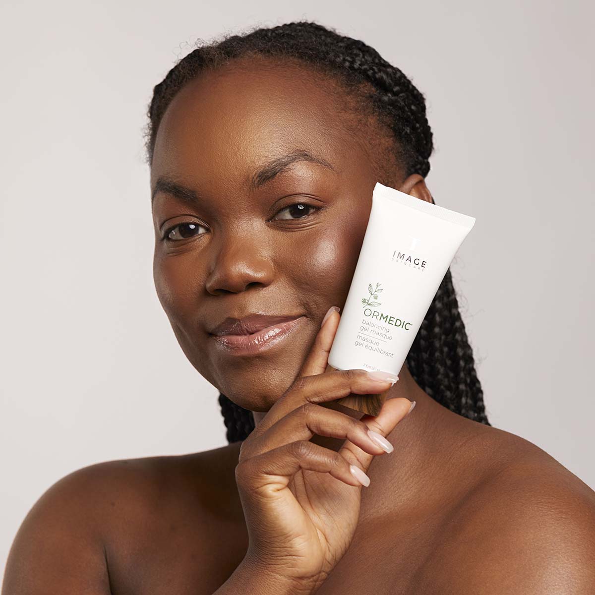 IMAGE SKINCARE Ormedic Balancing Gel Masque – Beruhigende Gelmaske, 59ml, Frau hält Tube neben Gesicht