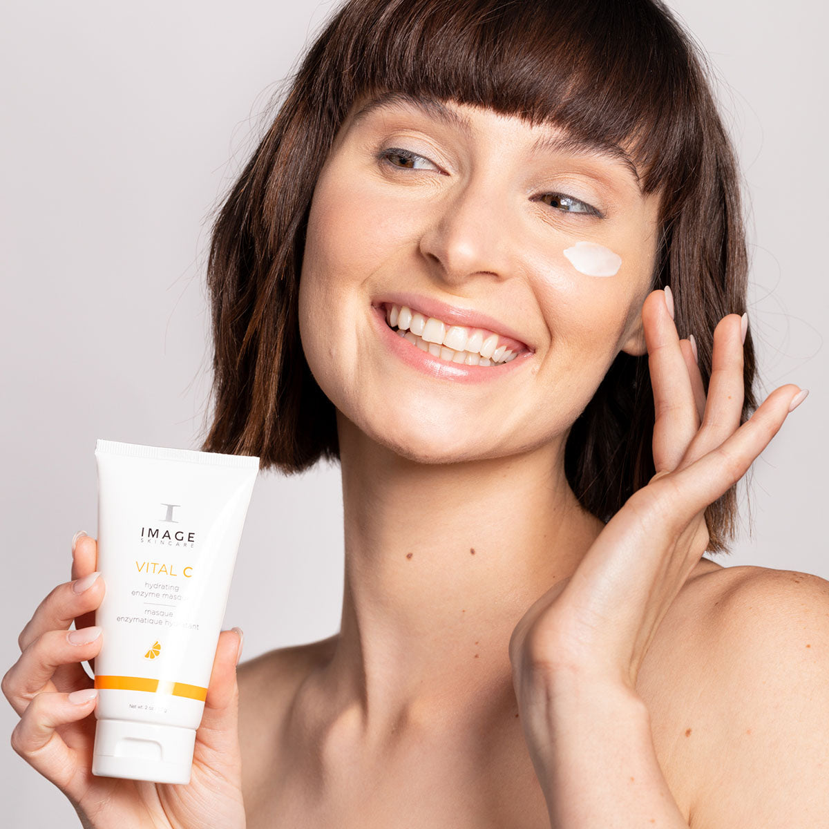 IMAGE SKINCARE Vital C Hydrating Enzyme Masque – 57g, Frau gibt Maske aus Gesicht