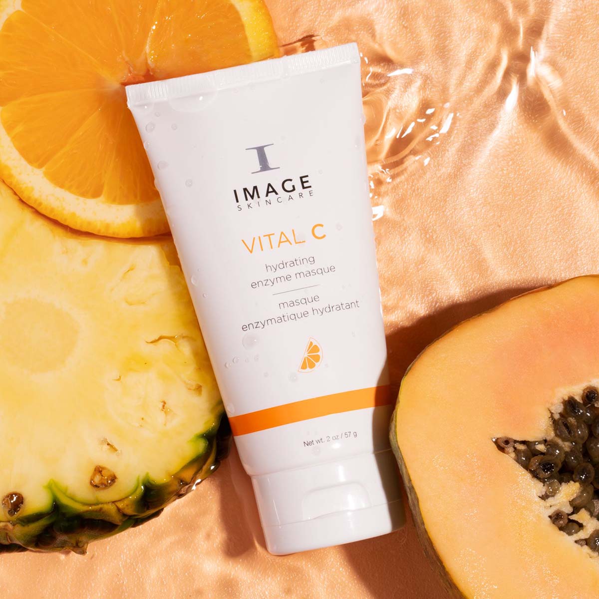IMAGE SKINCARE Vital C Hydrating Enzyme Masque – 57g, Tube liegend auf Ananas- und Orangenscheiben