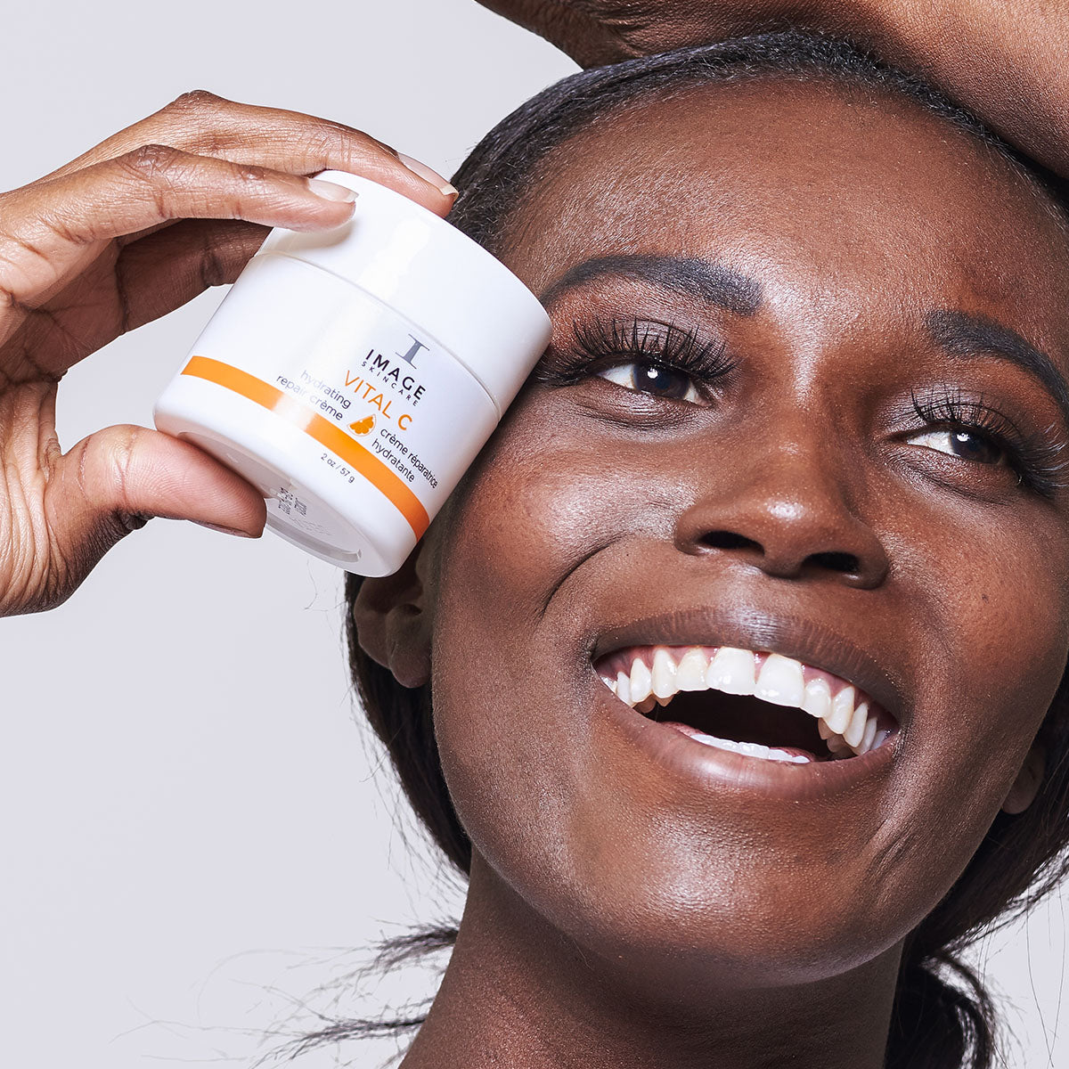 IMAGE SKINCARE Vital C Hydrating Repair Crème – regenerierende Nachtpflege, 57g, Frau hält Creme neben Gesicht