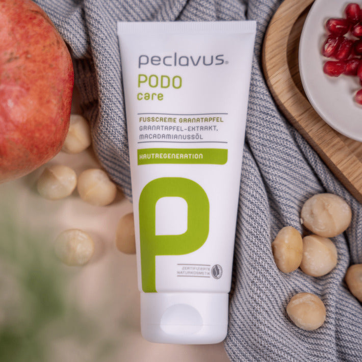 PECLAVUS Fußcreme Granatapfel  – 100ml, Tube liegend mit Granatapfel und Nüssen