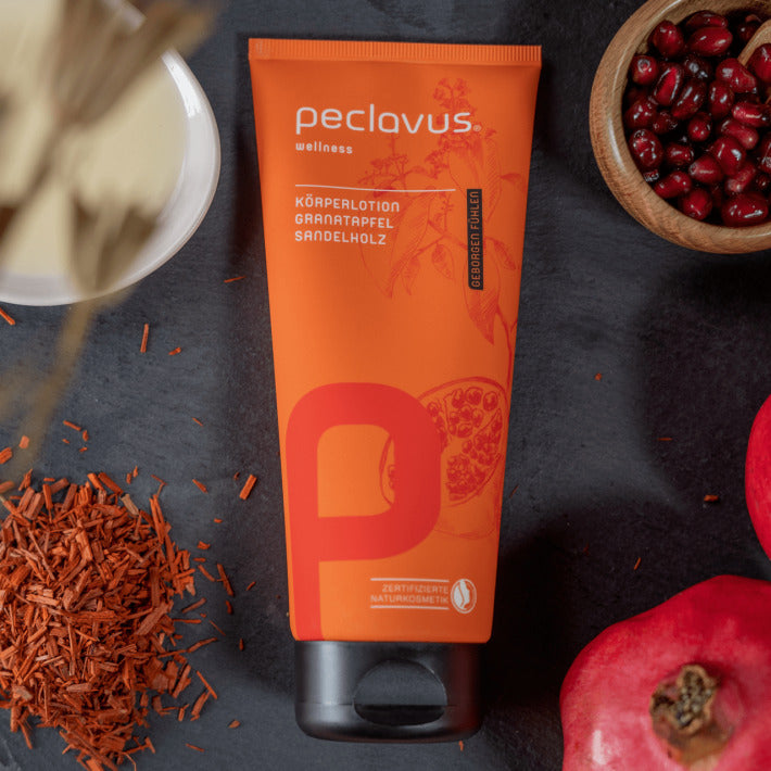 PECLAVUS Körperlotion Granatapfel Sandelholz  – 200ml, Tube liegend mit Granatapfelkernen