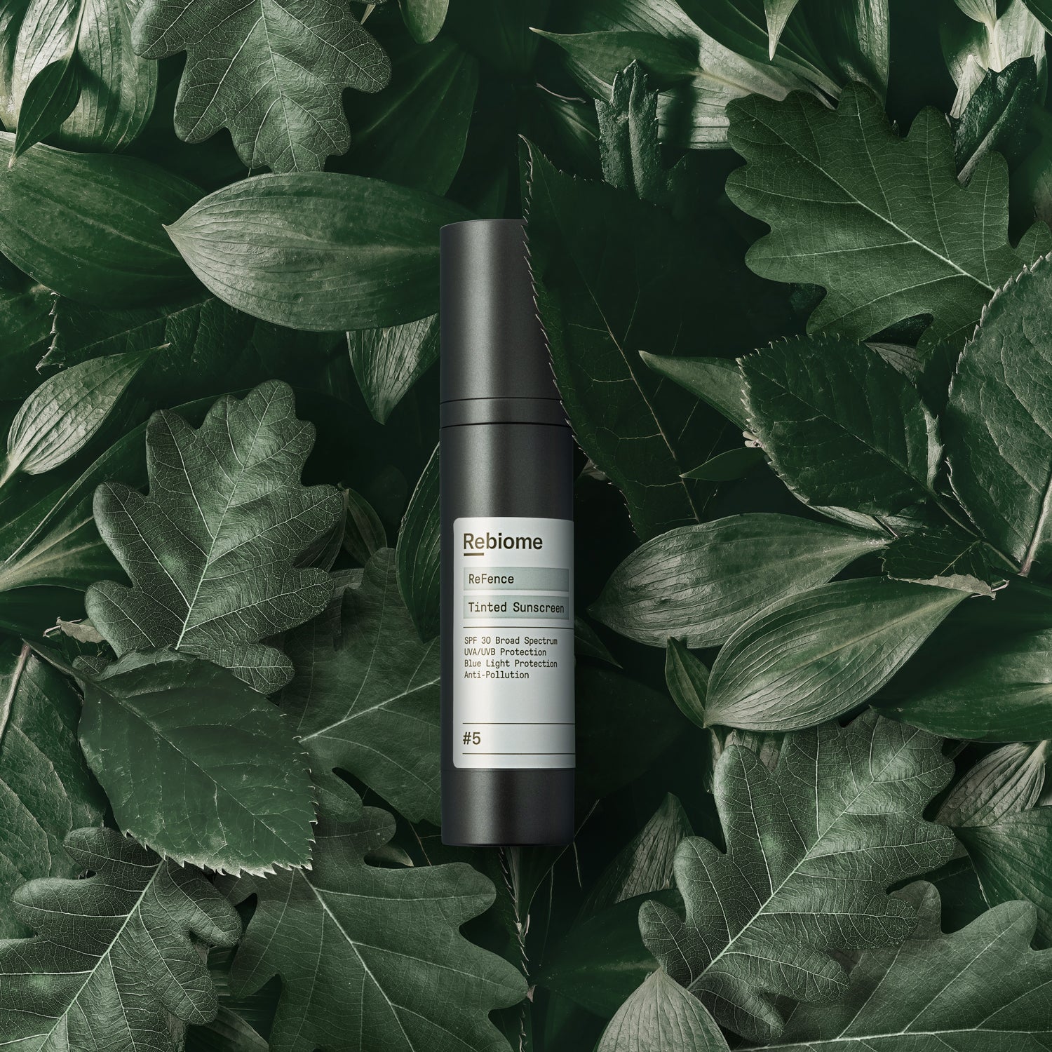 REBIOME ReFence Tinted Sunscreen SPF 30 – 50ml, Spender auf Laub liegend