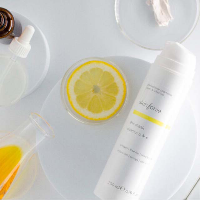 SKINFONIE the mask vitamin c & e  – Crememaske, 200ml, Spender liegend mit Zitronenschale und Laborutensilien
