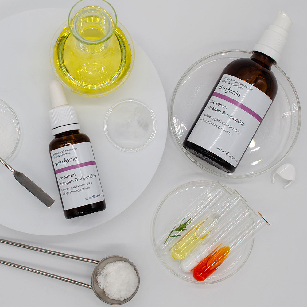 SKINFONIE  the serum collagen & tripeptide – Straffendes Anti-Age-Serum, 30ml+50ml, Pippetenflasche und Pumpspender liegend mit Laborutensilien