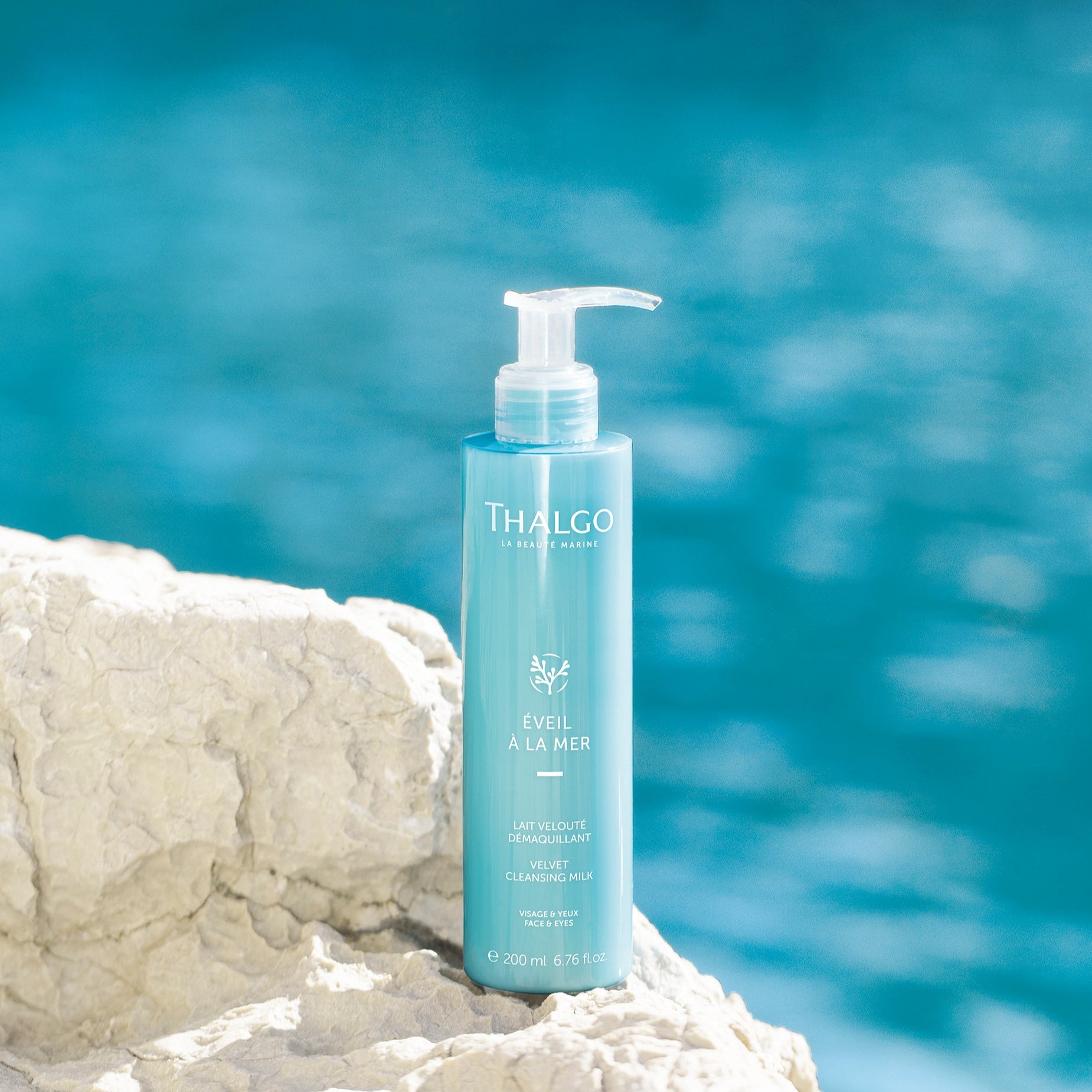 THALGO Éveil à la Mer - Zarte Reinigungsmilch – für trockene und sensitive Haut, 200ml, Pumpflasche auf Steinufer stehend am Meer