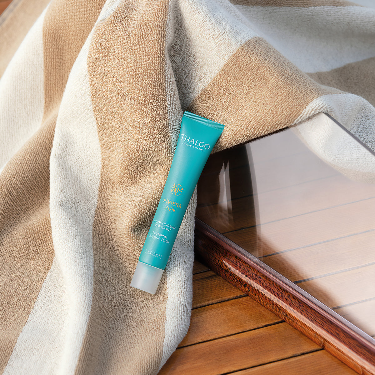 THALGO Riviera Sun Regenerierendes Aftersun-Fluid  – 50ml, Tube mit Handtuch auf Holzsteg