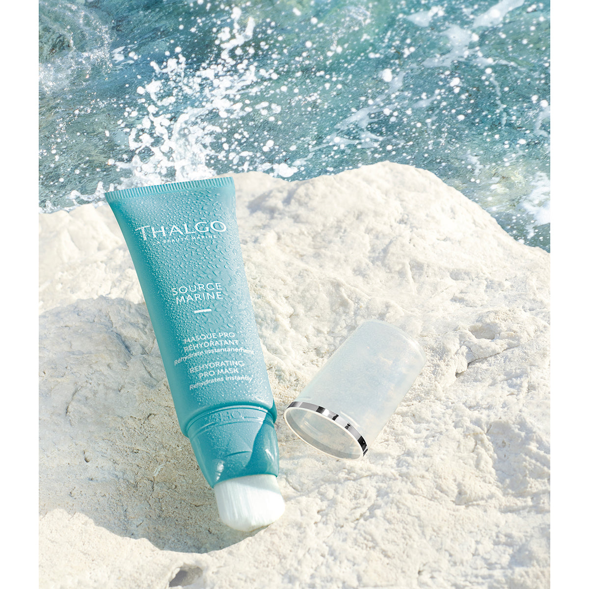 THALGO Source Marine - Masque Pro Réhydratant - Feuchtigkeitsspendende Maske – für feuchtigkeitsarme Haut, 50ml, Tube offen liegend auf Stein am Meer