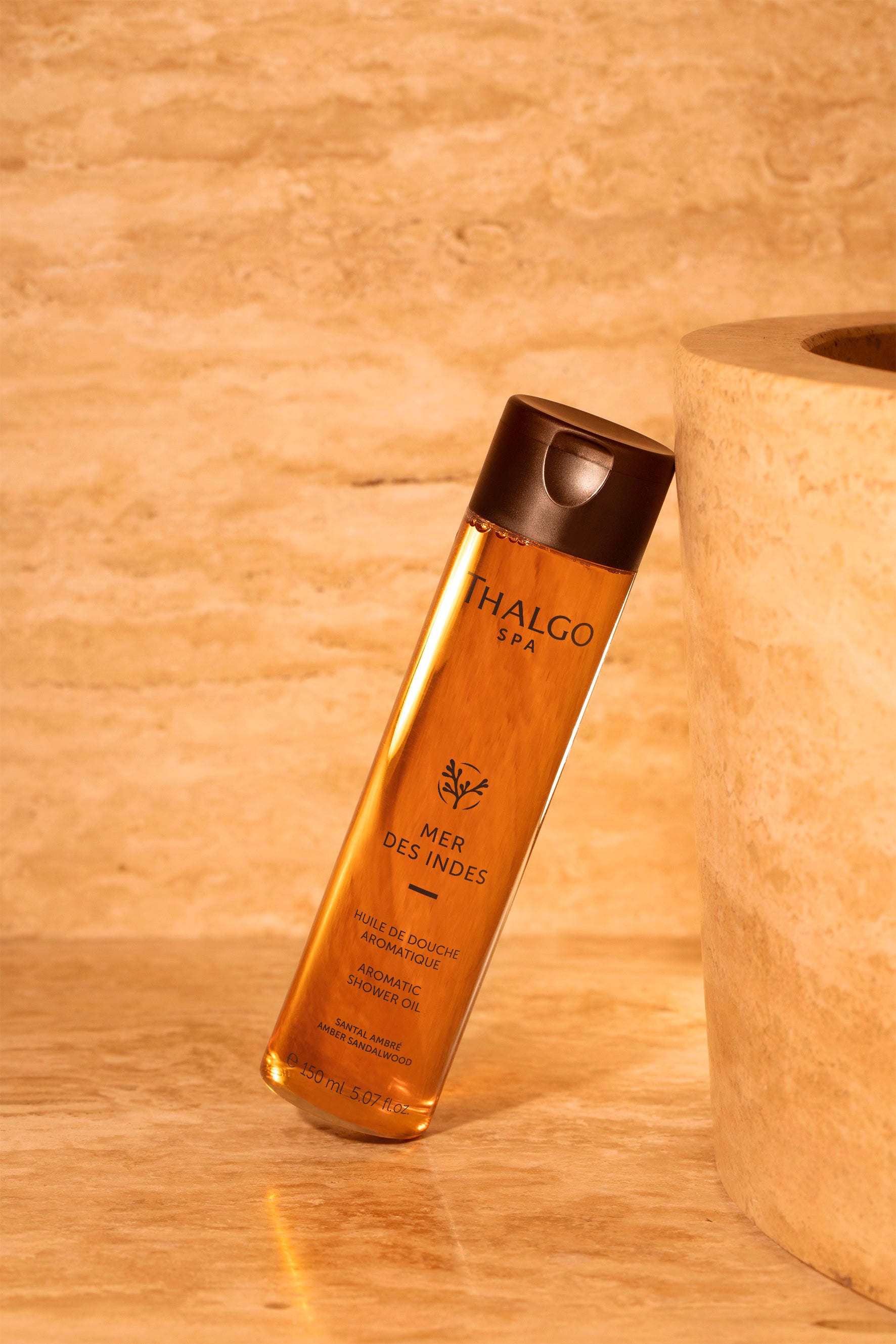 THALGO SPA Mer des Indes - Aroma-Duschöl  – 150ml, Spender auf Steinplatte gegen Steinbehälter gelehnt