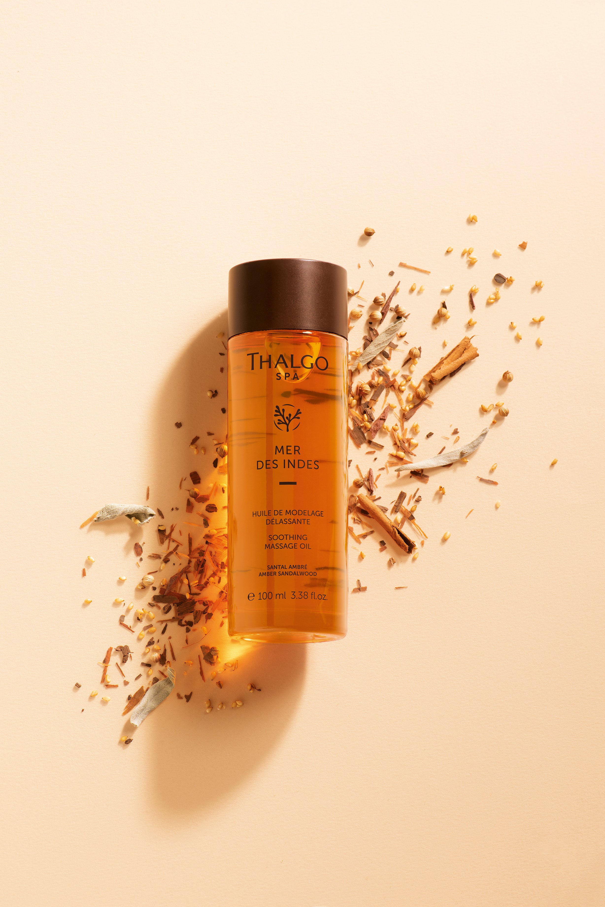 THALGO SPA Mer des Indes - Entspannendes Massageöl  – 100ml, Spenderflasche liegend auf Gewürzraspeln