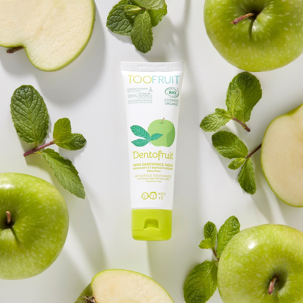 TOOFRUIT Dentofruit Zahncreme  – Apfel-Minze, 60g, Tube umringt von Äpfeln und Minzblättern
