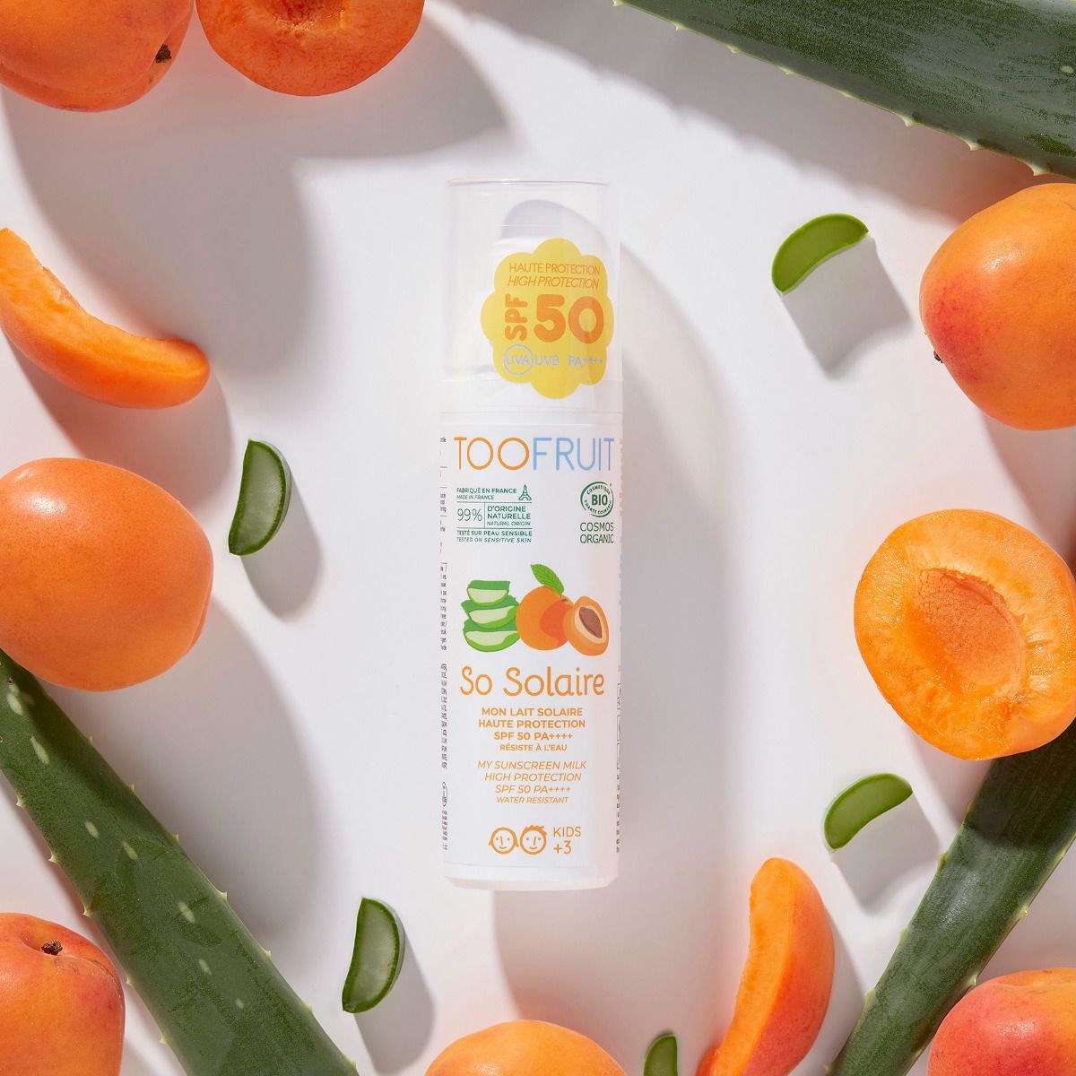 TOOFRUIT So Solaire Sonnenschutzcreme – LSF50+, 100ml, Pumpspender umringt von Aloe Vera Blättern und Aprikosen